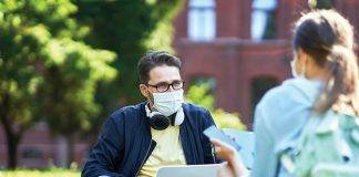 Students hanging out in the campus wearing protective masks and keeping distance due to coronavirus pandemic
