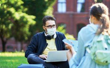 Students hanging out in the campus wearing protective masks and keeping distance due to coronavirus pandemic