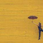 woman holding umbrella against a yellow background