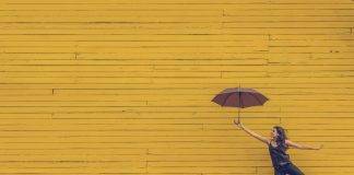 woman holding umbrella against a yellow background