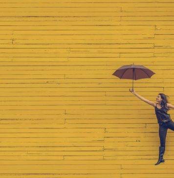woman holding umbrella against a yellow background