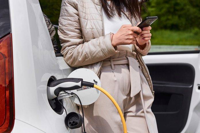 Young woman standing near the electric car