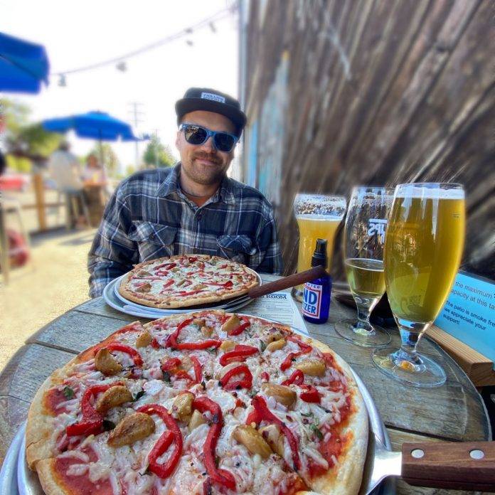 Man eating pizza at an outdoor eatery in Victoria BC
