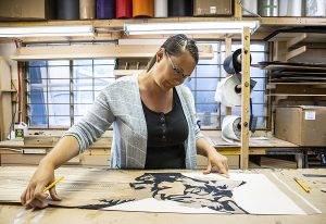 Angie Farquaharson of Kindred Snowboards, decals a snowboard in their workshop.