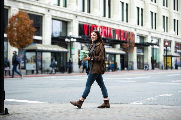 wide shot of woman walking on Douglas street in Victoria carrying an eco reusable container by Bread and Butter Collective