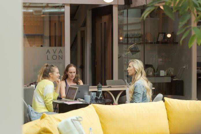 Three women sitting at a desk in the KWENCH co-working club