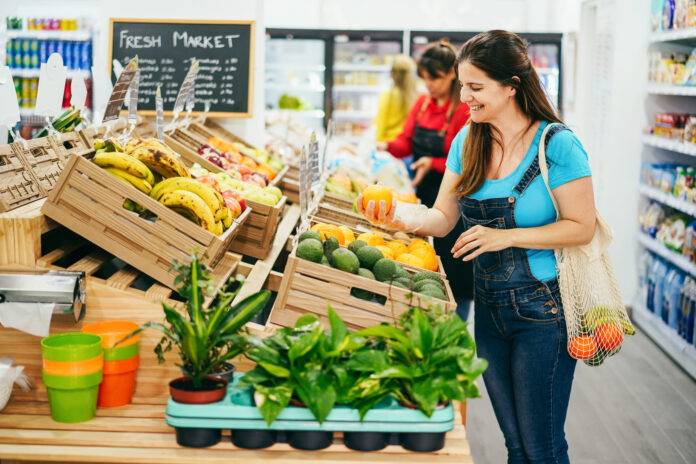 Female customer buying organic food fruits inside eco fresh market - Shopping concept - Focus on right woman face